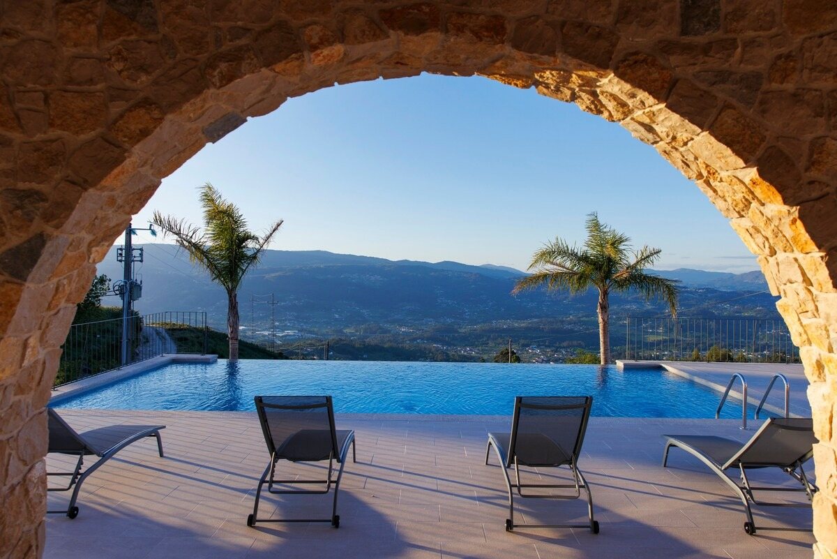 Piscina infinita vista através de um arco de pedra